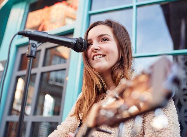 female-musician-busking-playing-acoustic-guitar-QGPZ2UP.jpg